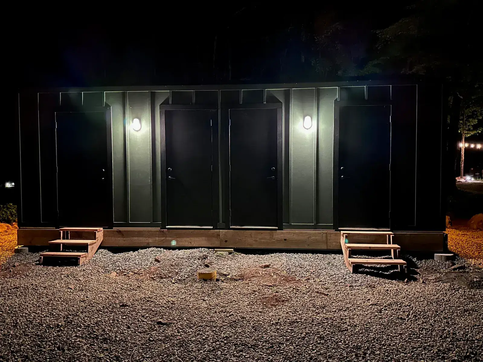 A row of private-door stalls on a Pine mobile bathhouse at dusk