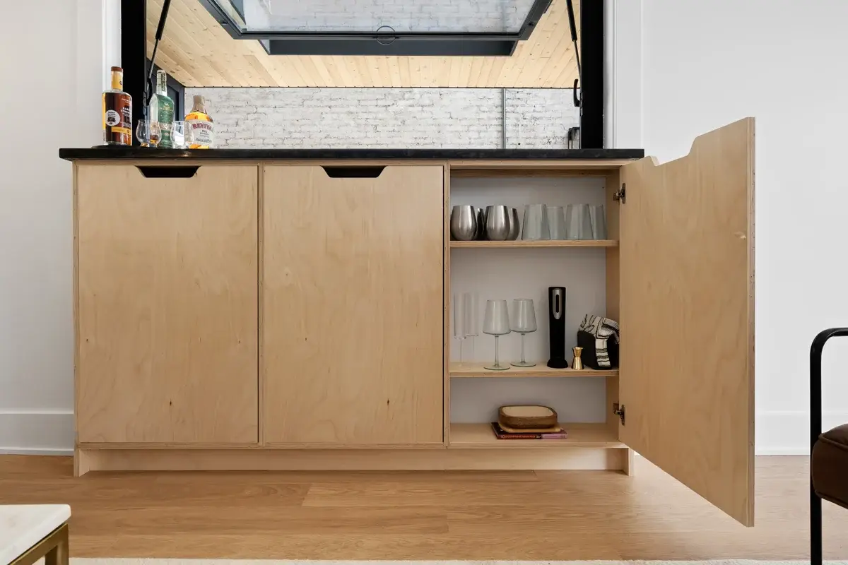Built-in cabin bar cabinet with glassware and a stone counter under a pass-through window