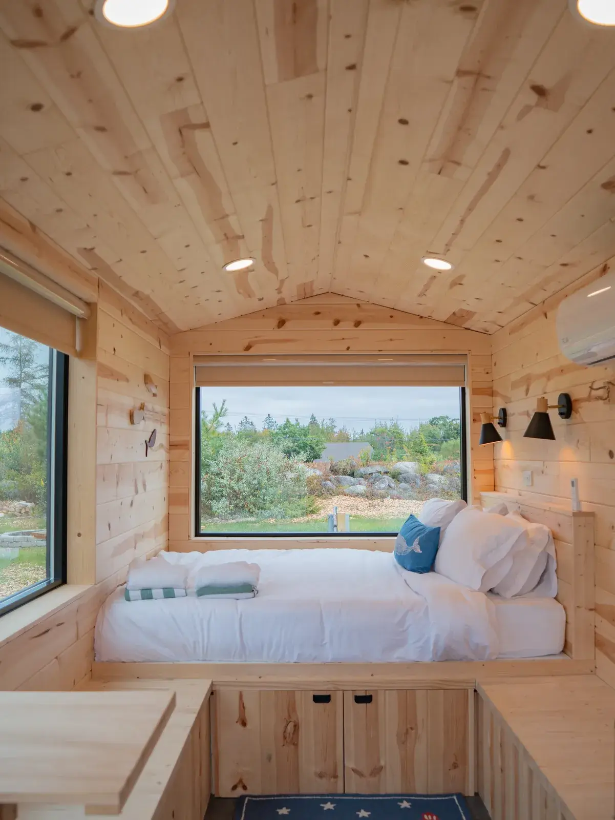 Cabin interior with a bed facing a forest window