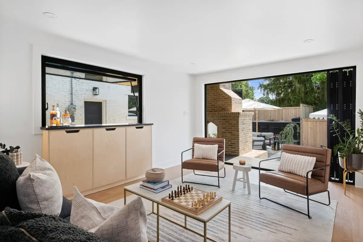 Cabin living room with leather chairs opening to a patio through a folding glass wall