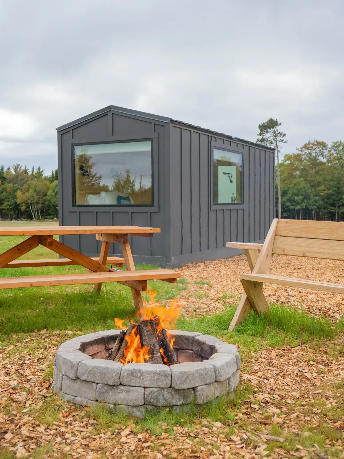 A Pine cabin with a picnic table and a lit firepit